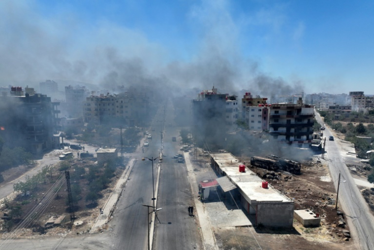 Une vue aérienne montre de la fumée s'élevant de la ville de Soueida dans le sud de la Syrie, le 19 juillet 2025 ( AFP / Omar HAJ KADOUR )