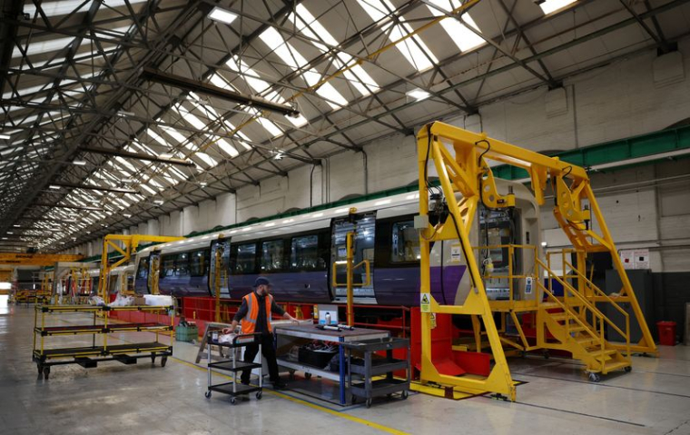 Un ouvrier marche à côté d'un train de la ligne Elizabeth partiellement achevé à l'usine Alstom de Derby