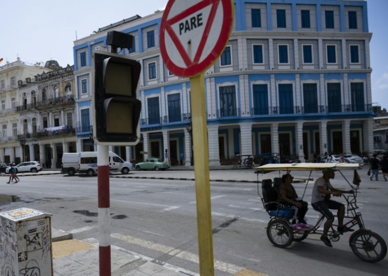 Un vélo-taxi passe devant un feu de signalisation éteint en raison d'une coupure de courant à La Havane, le 4 mars 2026 ( AFP / YAMIL LAGE )