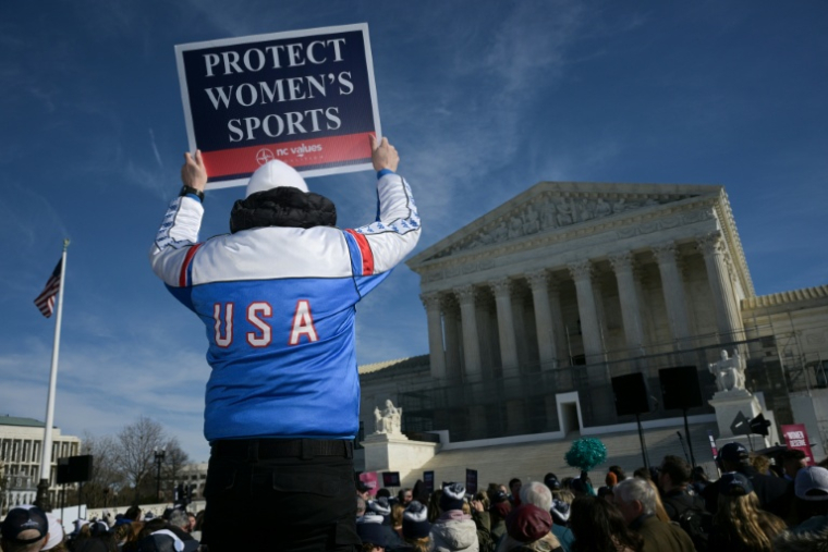 Un homme tient une affiche contre la participation des personnes transgenres aux compétitions sportives féminines devant la Cour suprême américaine, à Washington, le 13 janvier 2026 ( AFP / Oliver Contreras )