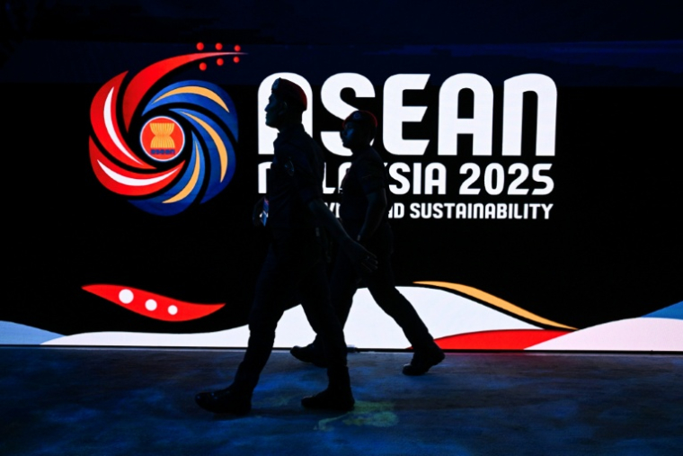 Des membres de la police royale de Malaisie passent devant le logo du 47e sommet de l'Association des nations de l'Asie du Sud-Est (Asean), le 25 octobre 2025 à Kuala Lumpur. ( AFP / Mohd RASFAN )
