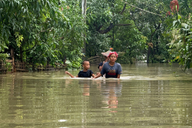 Des habitants se frayent un chemin dans l'eau après des inondations causées par des pluies de mousson à Kyauktaw, dans l'ouest de la Birmanie, le 10 juillet 2026  ( AFP / STR )
