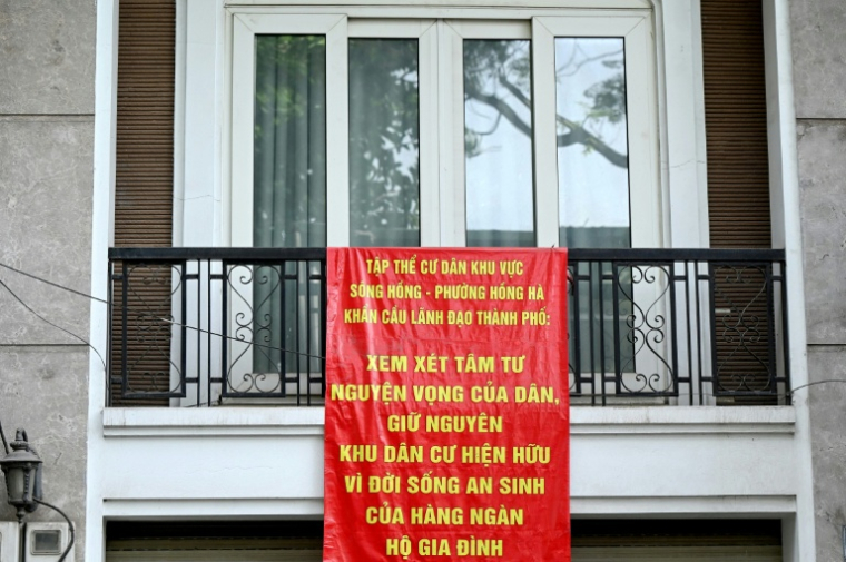 Une banderole de protestation contre un vaste projet de réaménagement accrochée au balcon d'un immeuble dans une rue d'un quartier de Hanoï, le 19 juin 2026 au Vietnam ( AFP / STR )