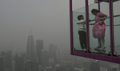 Des personnes dans un point de vue surplombant la ligne d'horizon de la capitale Kuala Lumpur, noyée dans les fumées toxiques issues des incendies en Indonésie, le 16 octobre 2026, en Malaisie ( AFP / Jam STA ROSA )