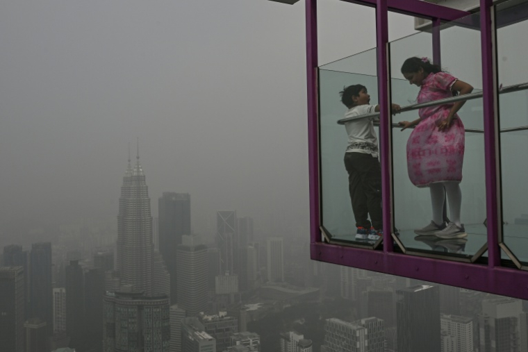 Des personnes dans un point de vue surplombant la ligne d'horizon de la capitale Kuala Lumpur, noyée dans les fumées toxiques issues des incendies en Indonésie, le 16 octobre 2026, en Malaisie ( AFP / Jam STA ROSA )