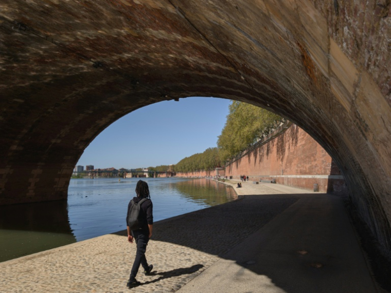 Un passant le long de la Garonne à Toulouse lors d'un pic de chaleur, le 8 avril 2026 ( AFP / Ed JONES )