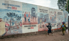 Des piétons passent devant des illustrations de sensibilisation à Ebola affichées sur les panneaux du Centre de traitement d'Ebola (ETC) à Munigi, en RDC, le 2 juin 2026. ( AFP / Jospin Mwisha )