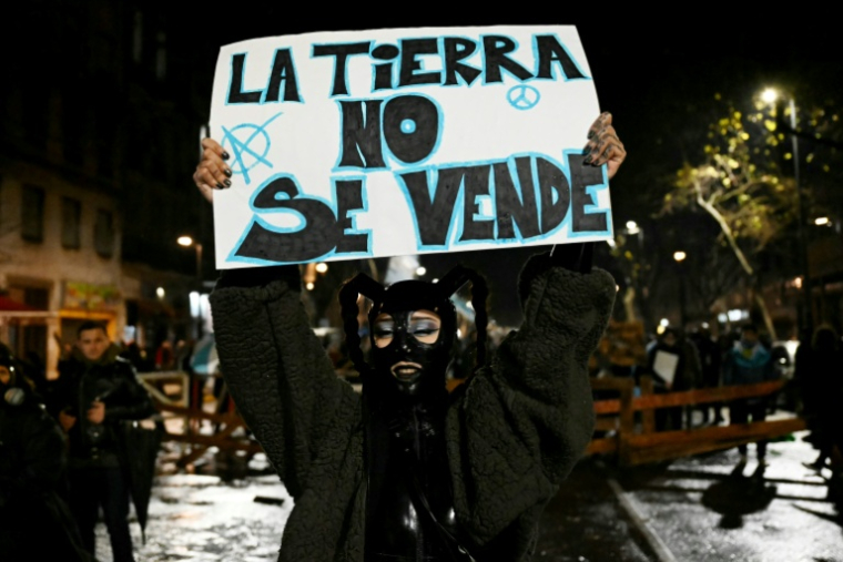 Une manifestante porte un écriteau "La terre n'est pas à vendre" lors d'un rassemblement à Buenos Aires, le 6 août 2026 ( AFP / Luis ROBAYO )