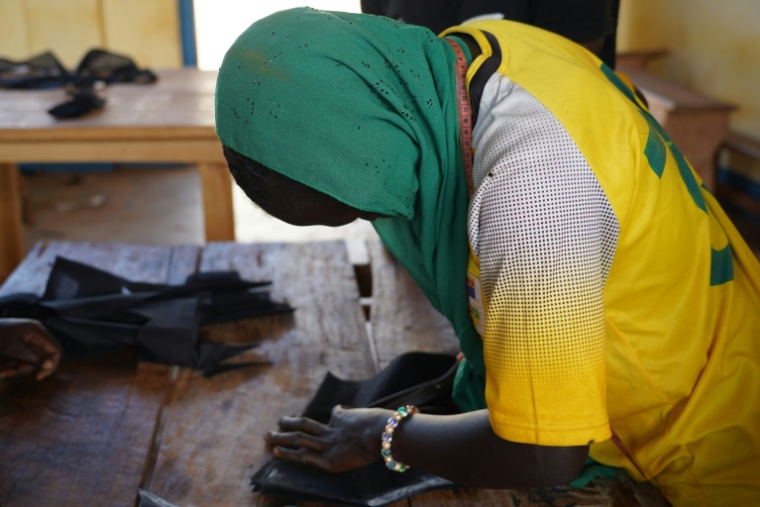 Un élève, ancien enfant soldat, découpe un morceau de tissu lors d’un cours de couture au Centre de formation professionnelle pratique et d’alphabétisation de Bria, en Centrafrique, le 1er avril 2026 ( AFP / Mariam KONE )