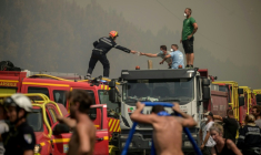Un pompier tend un masque à un volontaire en pleine lutte contre un feu de forêt à Lanton, à l'est du bassin d'Arcachon et à l'ouest de Bordeaux, le 29 juillet 2026 ( AFP / Ed JONES )