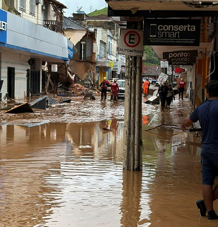 Photo fournie par le Service incendie du Minas Gerais montrant des pompiers dans une rue inondée après des fortes pluies à Juiz de Fora, dans l'Etat du Minas Gerais, le 24 février 2026 au Brésil ( Service incendie du Minas Gerais / Handout )