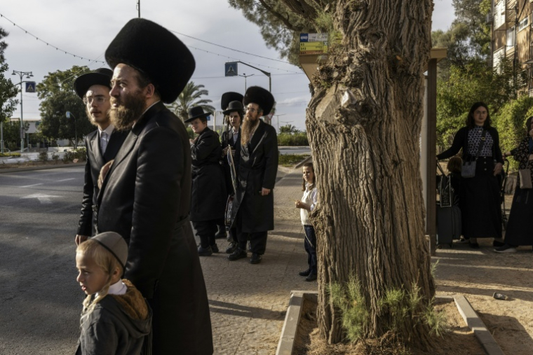 Des juifs ultra-orthodoxes à un arrêt de bus à Arad le 1er octobre 2026 ( AFP / JOHN WESSELS )