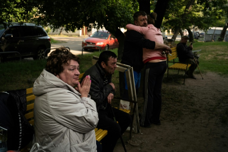 Des habitants choqués devant un immeuble endommagé par des frappes russes à Kharkiv, le 11 juin 2025 en Ukraine ( AFP / Florent VERGNES )