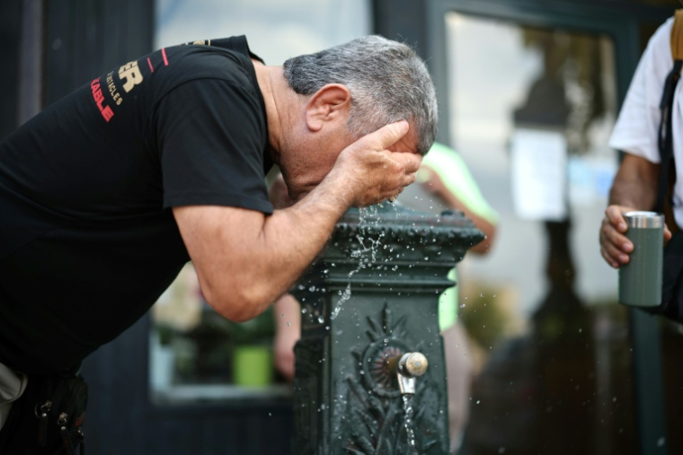 Un homme se rafraichit à une fontaine publique à Paris le 18 juin 2026 ( AFP / SIMON WOHLFAHRT )