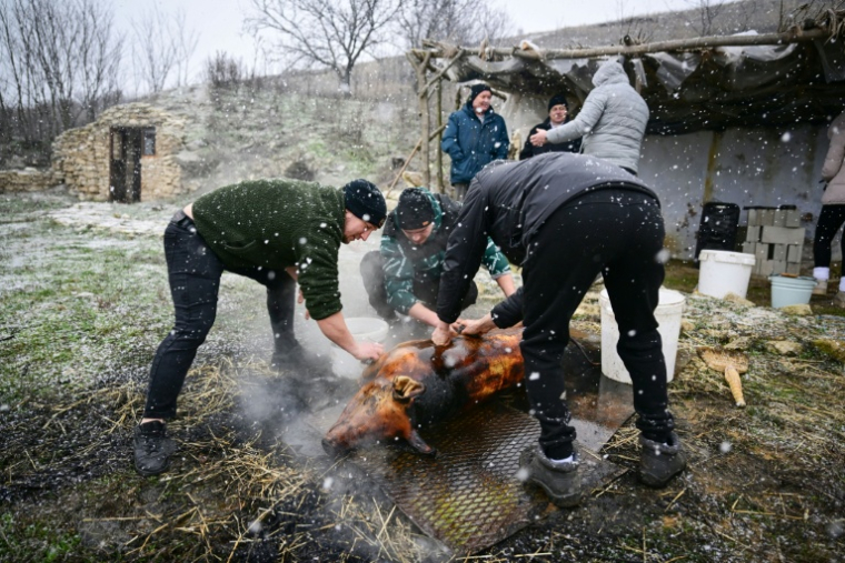 Des hommes du village de Rogojeni préparent un cochon rôti, le 4 janvier 2026 en Moldavie ( AFP / Daniel MIHAILESCU )