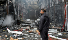 Un homme observe les dégâts alors qu'un pompier ukrainien éteint un incendie au marché "Barabashovo" après une attaque de drone à Kharkiv, le 6 mai 2025 en Ukraine ( AFP / SERGEY BOBOK )