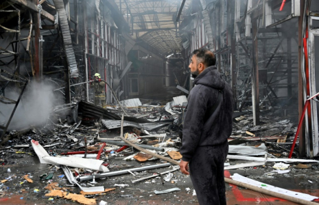 Un homme observe les dégâts alors qu'un pompier ukrainien éteint un incendie au marché "Barabashovo" après une attaque de drone à Kharkiv, le 6 mai 2025 en Ukraine ( AFP / SERGEY BOBOK )