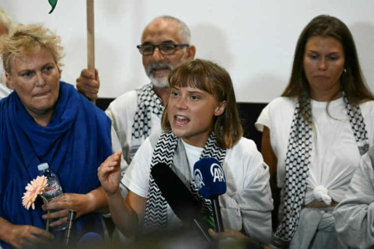 La militante suédoise pour le climat Greta Thunberg (au centre) prononce un discours à son arrivée à l'aéroport d'Athènes le 6 octobre 2025, aux côtés de militants qui naviguaient à bord de la flottille pour Gaza avant d'être arrêtés et expulsés par les forces israéliennes. ( AFP / Aris MESSINIS )