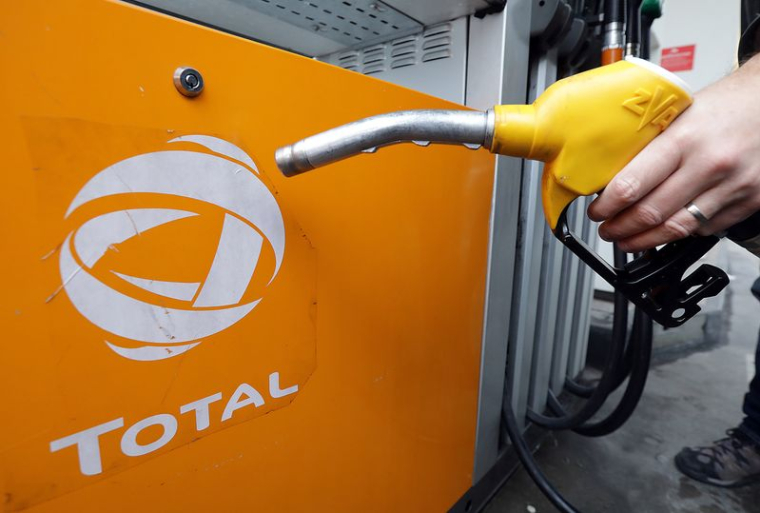 Un client tient une pompe à essence alors qu'il fait le plein de sa voiture dans une station Total à Nice
