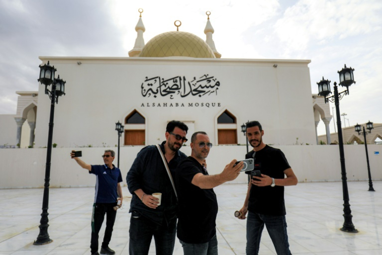 Des passants posent pour un selfie devant la mosquée Sahaba, dans la ville de Derna, dans l'est de la Libye, le 15 mai 2026, après des efforts de reconstruction et de réurbanisation entrepris plus de deux ans après les pluies extrêmes provoquées par la tempête Daniel ( AFP / Abdullah DOMA )