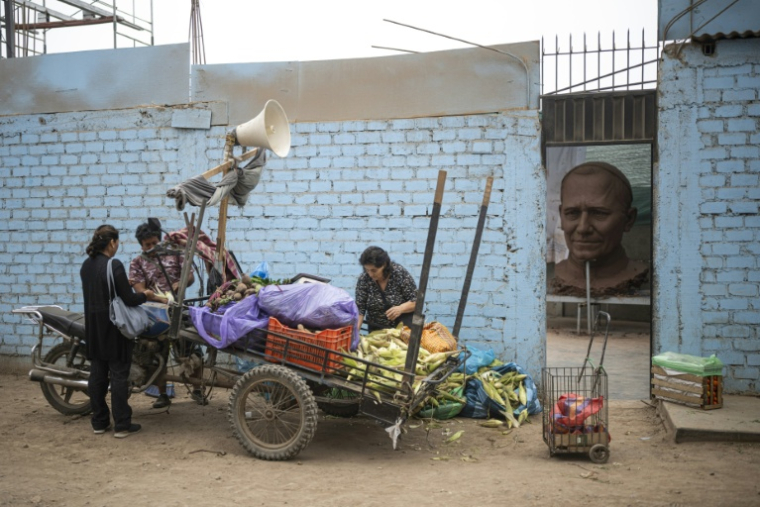 Un vendeur ambulant vend des légumes devant l'atelier où est réalisée une statue géante du pape Léon XIV, dans le quartier de Carabayllo, dans la périphérie nord de Lima, le 25 septembre 2026 ( AFP / ERNESTO BENAVIDES )