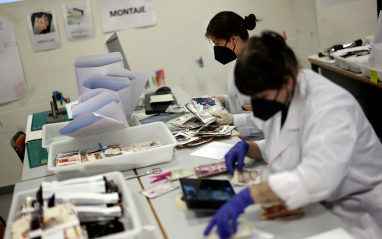 Des étudiants de l'Université des Beaux-Arts nettoient et restaurent des photos de famille par la boue pendant les inondations, le 2 octobre 2025 à Valence, en Espagne ( AFP / Thomas COEX )