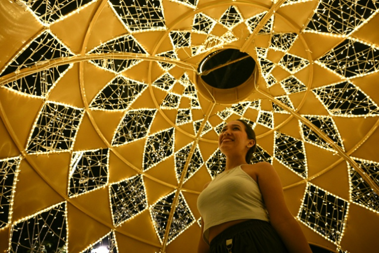 Une femme sous les décorations de Noël à Caracas, le 19 décembre 2025 au Venezuela ( AFP / Federico PARRA )
