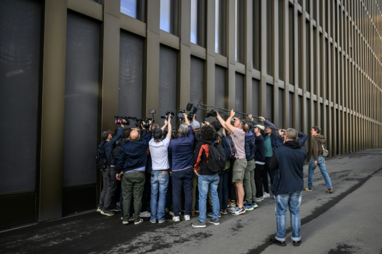 Des journalistes autour d'un avocat, à Sion (Suisse), le 5 juin 2026, avant une confrontation entre les propriétaires du bar Le Constellation, à Crans-Montana, qui a brûlé la nuit du Nouvel an ( AFP / Fabrice COFFRINI )