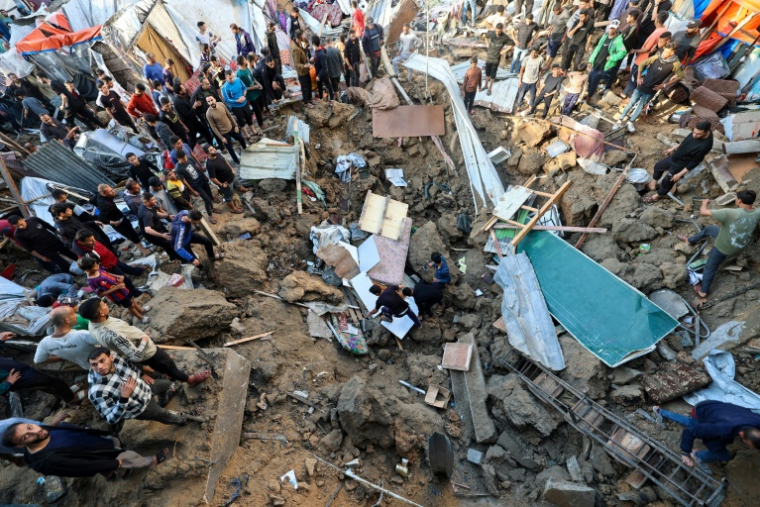 Des Palestiniens recherchent des survivants dans un cratère sur le site d'une frappe israélienne contre une école de l'UNRWA abritant des déplacés à Bureij, dans le centre de la bande de Gaza, le 6 mai 2025 ( AFP / Eyad BABA )