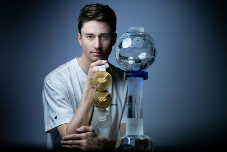 Le biathlète Éric Perrot pose avec ses trois médailles olympiques et son globe de cristal lors d'une séance photo à Paris, le 25 mars 2026 ( AFP / JOEL SAGET )