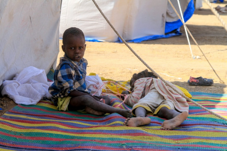 Des enfants originaires d'El-Facher devant leur tente dans un camp pour personnes déplacées, à d'Al-Dabba, dans le nord du Soudan, le 13 novembre 2025 ( AFP / - )