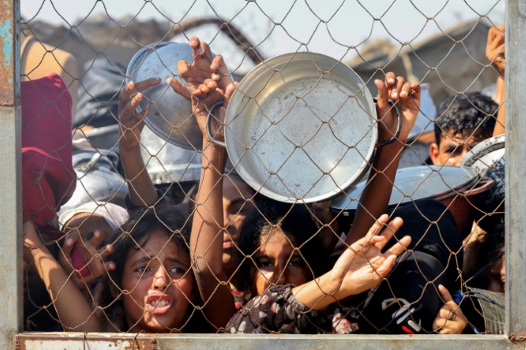 Des Palestiniens, principalement des enfants, se bousculent pour recevoir un repas chaud dans une cuisine opérée par une organisation de charité locale à al-Mawassi dans le sud de la bande de Gaza, le 22 juillet 2025 ( AFP / - )