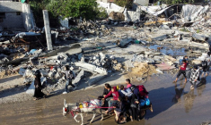 Des Palestiniens déplacés rentrent chez eux et passent devant une maison détruite par une attaque israélienne à Khan Younis, pendant la trêve conclue entre le Hamas et Israël