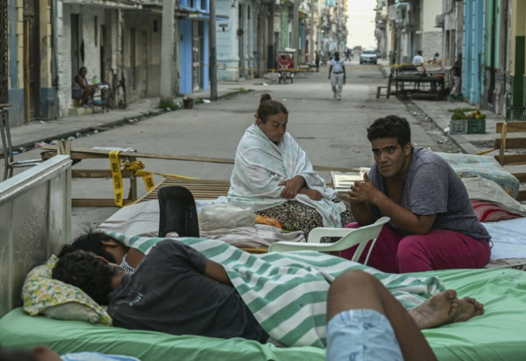 Plusieurs familles passent la nuit sur des lits installés dans la rue, dans un quartier central de La Havane, le 30 juillet 2026, après l'effondrement partiel de leur immeuble ( AFP / YAMIL LAGE )