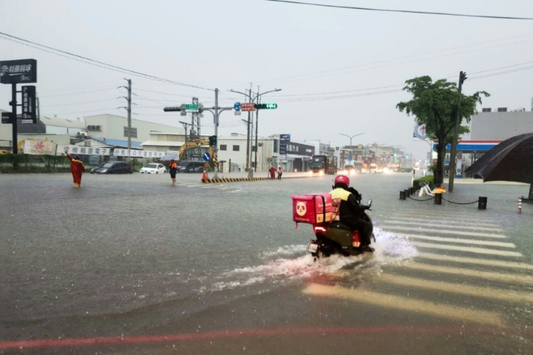 Photo fournie par le Bureau des pompiers de la ville de Tainan, montrant un livreur à scooter qui traverse une intersection inondée à Tainan sur l'île de Taïwan, le 2 août 2025. ( Tainan City Government Fire Bureau / Handout )