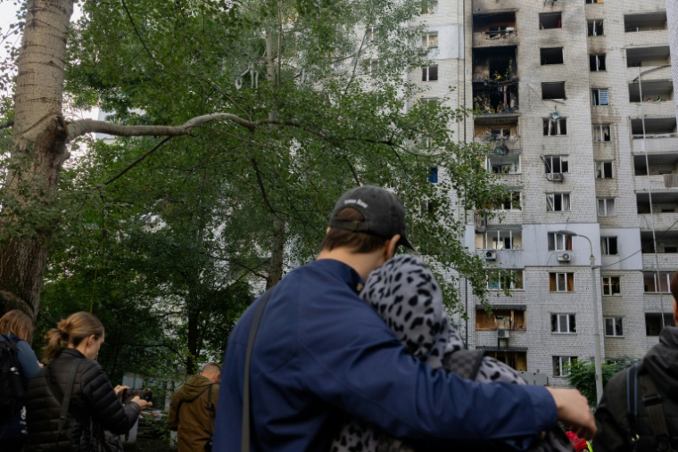 Des habitants observent un immeuble résidentiel endommagé après une frappe de drone russe à Kiev, le 25 septembre 2026 ( AFP / Tetiana DZHAFAROVA )