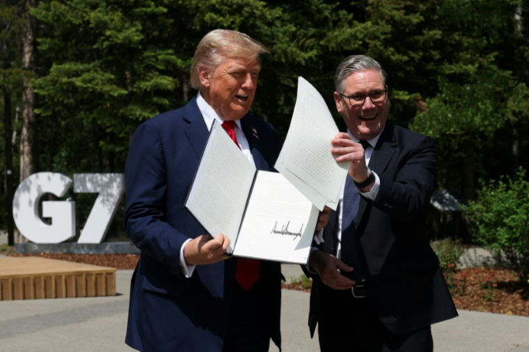 Le président américain Donald Trump (g) tient un accord commercial signé entre les Etats-Unis et le Royaume-Uni à côté du Premier ministre britannique Keir Starmer à Kananaskis, au Canada, le 16 juin 2025 ( POOL / Suzanne Plunkett )