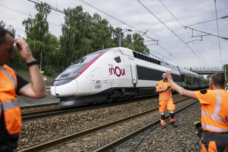 Un TGV Inoui passe près de techniciens de la SNCF qui travaillent à reconnecter les câbles ferroviaires à la gare de Mont-de-Terre à Lille, le 25 juin 2025 dans le Nord ( AFP / Sameer Al-DOUMY )