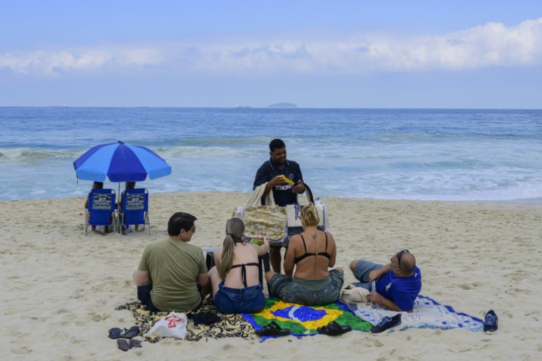 Un vendeur reçoit un paiement via le système de paiement instantané brésilien PIX sur la plage de Copacabana, à Rio de Janeiro, le 9 juillet 2026 au Brésil ( AFP / Pablo PORCIUNCULA )