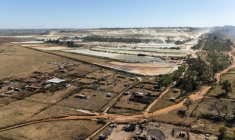 Vue aérienne de parcelles agricoles et de talus miniers en arrière-plan, dans le quartier de Snake Park, à Soweto, le 30 mai 2025 en Afrique du Sud ( AFP / EMMANUEL CROSET )