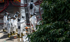 Des policiers de l'unité d'identification des victimes de catastrophes, vêtus d'une combinaison de protection, examinent le complexe résidentiel de Wang Fuk Court après l'incendie qui l'a ravagé, à Hong Kong le 29 novembre 2025 ( AFP / Philip FONG )