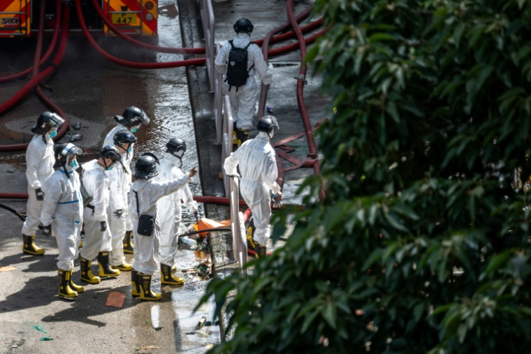 Des policiers de l'unité d'identification des victimes de catastrophes, vêtus d'une combinaison de protection, examinent le complexe résidentiel de Wang Fuk Court après l'incendie qui l'a ravagé, à Hong Kong le 29 novembre 2025 ( AFP / Philip FONG )