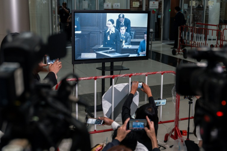 Des membres des médias devant un écran montrant la Première ministre thaïlandaise suspendue Paetongtarn Shinawatra lors d'une procédure devant la Cour constitutionnelle de Bangkok, le 21 août 2025 ( AFP / Chanakarn Laosarakham )