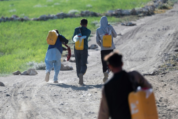 Des habitants transportent des bidons d'eau dans la banlieue de Kaboul, le 27 avril 2025 en Afghanistan ( AFP / Wakil KOHSAR )