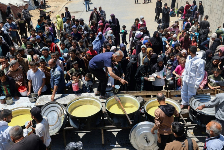 Des Palestiniens font la queue pour obtenir un repas chaud lors d'une distribution alimentaire au camp de réfugiés de Nousseirat, dans le centre de la bande de Gaza, le 4 mai 2025 ( AFP / Eyad BABA )