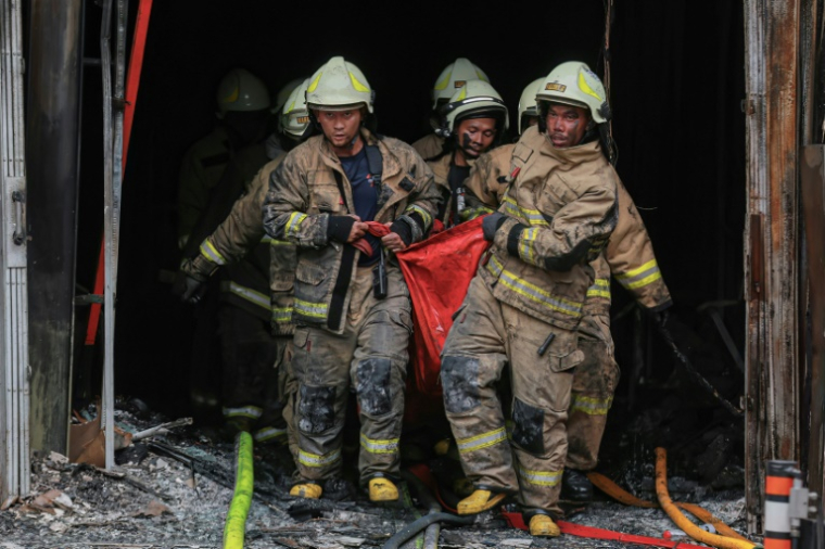 Des pompiers évacuent le corps d'une victime de l'incendie d'un immeuble à Jakarta le 9 décembre 2025 ( AFP / SYNATRIA RESPATI )