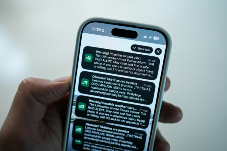 Une personne regarde sur son téléphone portable des avertissements de possible raid aérien à Vilnius, le 20 mai 2026 en Lituanie ( AFP / Andrei SHAULIUHA )