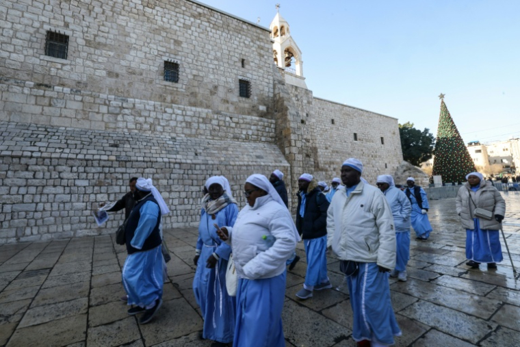 Des religieuses et moines chrétiens passent devant l'église de la Nativité à Bethléem, en Cisjordanie occupée, avant les célébrations de Noël, le 24 décembre 2025 ( AFP / HAZEM BADER )