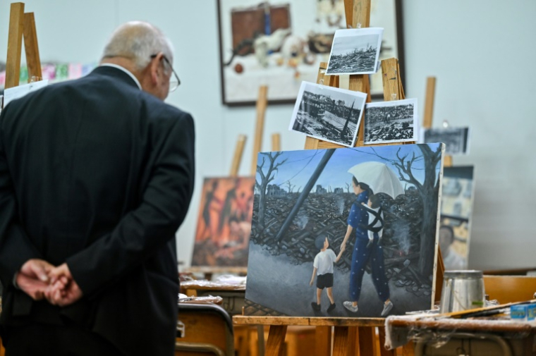 Masaki Hironaka, un survivant de la bombe atomique, regarde une peinture réalisée par un élève dans le cadre d'un projet destiné à préserver les témoignages des survivants, le 29 mai 2025 à Hiroshima ( AFP / Richard A. Brooks )