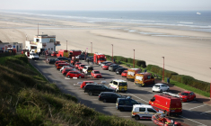 Des véhicules de secours et des équipes médicales sur un parking surplombant la plage après qu'une tentative de traversée illégale de la Manche a tourné au drame, à Equihen-Plage, le 9 avril 2026 dans le Pas-de-Calais ( AFP / Sameer AL-DOUMY )